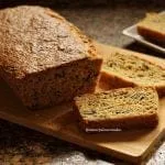 Pão caseiro sobre tábua de bambu já fatiado. Ao lado do pão duas fatias deitadas sobre a tábua