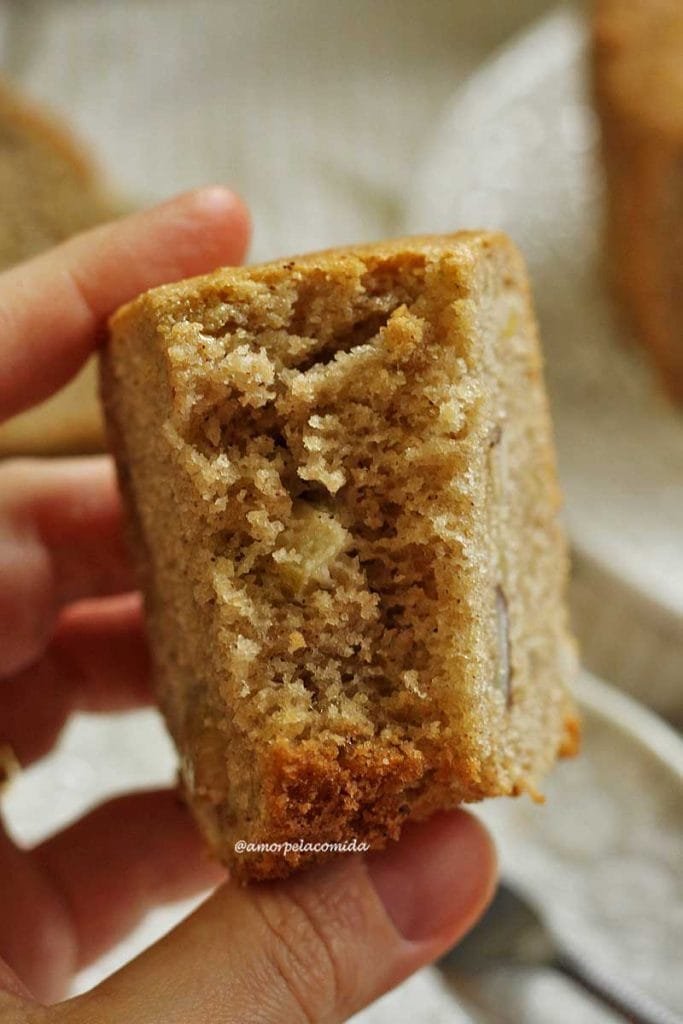 Mão segurando pedaço de bolo de castanha mordido