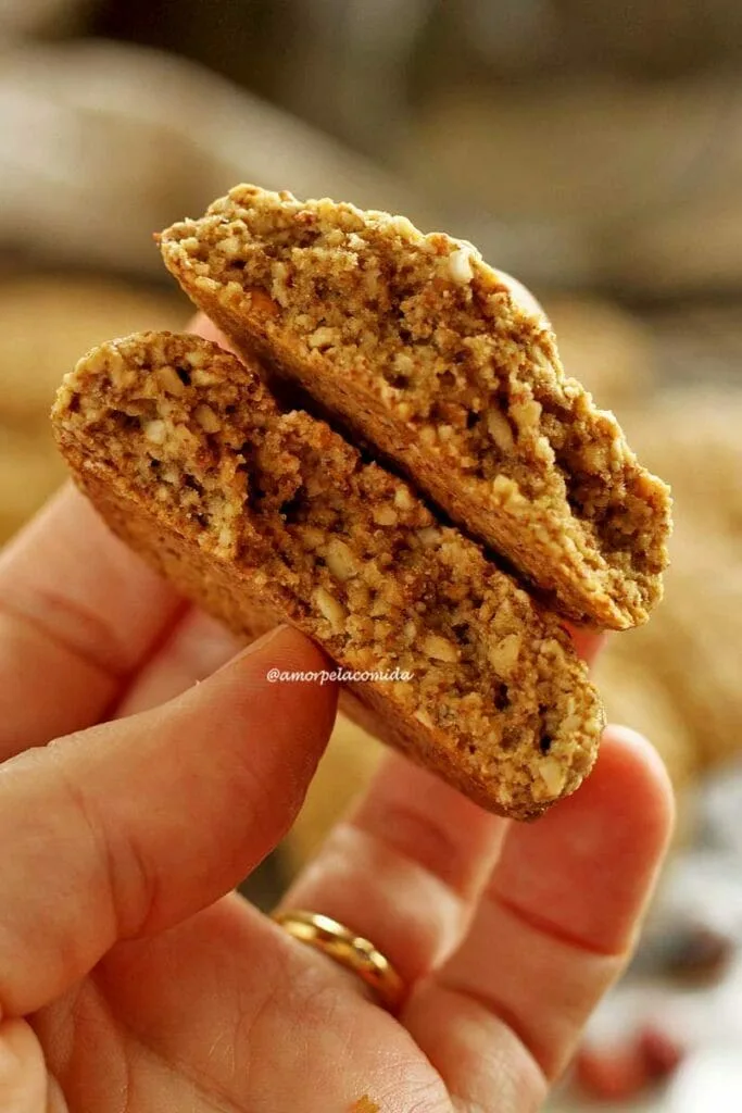 Main tenant un biscuit aux arachides coupé en deux montrant la texture intérieure légèrement aérée