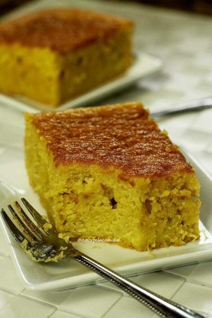 Fatia de bolo de pamonha faltando um pedacinho, o garfinho sujo do bolo está ao lado