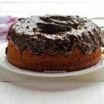 Bolo de ameixa redondo com furo no meio com cobertura cremosa de ameixa preta sobre prato branco