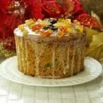 Panetone sobre prato branco com cobertura de glacê de açúcar e frutas cristalizadas no topo