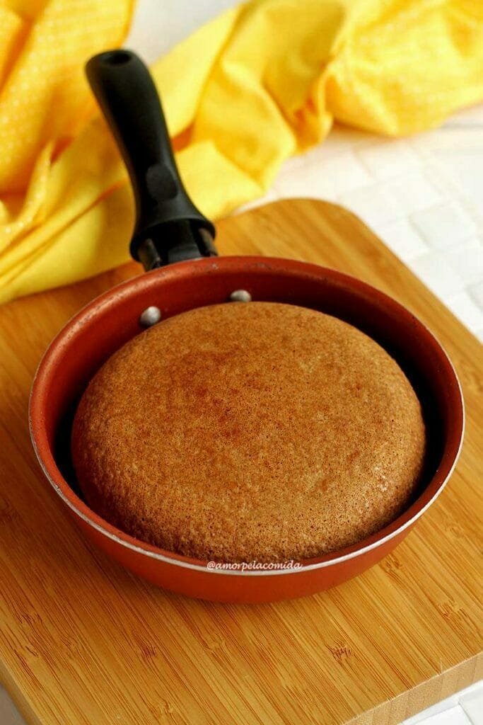 Frigideira pequena com bolo de fubá dentro sobre tábua de madeira quadrada