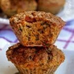 Dois muffins salgados empilhados, o de cima está mordido mostrando pedacinhos de espinafre e tomate