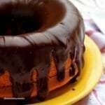 Bolo de cenoura com furo no meio com cobertura de chocolate cremosa e brilhante, sobre prato amarelo