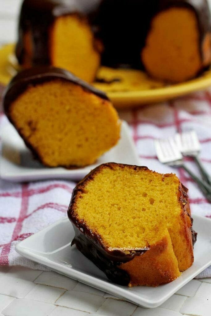 Duas fatias de bolo de cenoura com cobertura de chocolate, a da frente está deitada no prato e a de trás está de pé