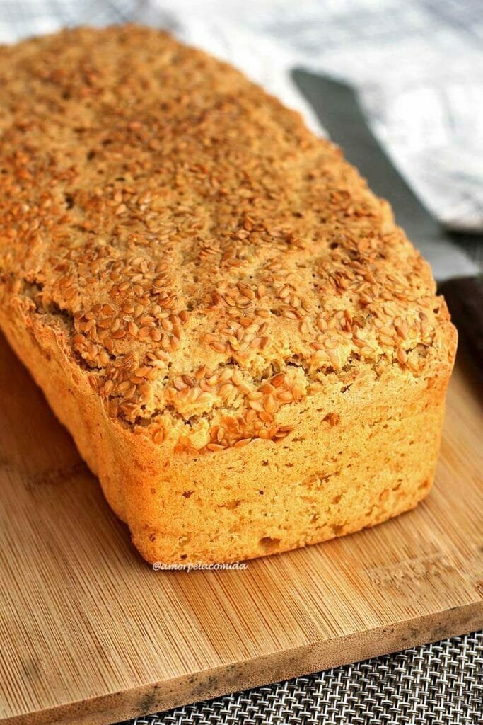 Pão de forma sobre tábua de madeira, no topo do pão sementes de linhaça para decorar