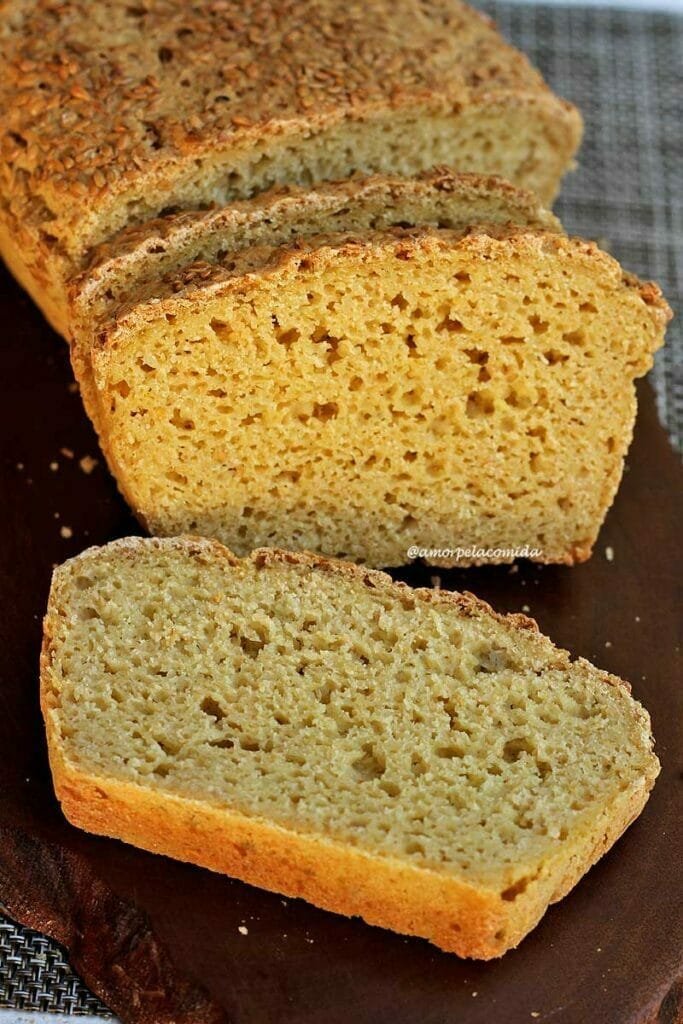 Pão fatiado sobre tábua de madeira escura