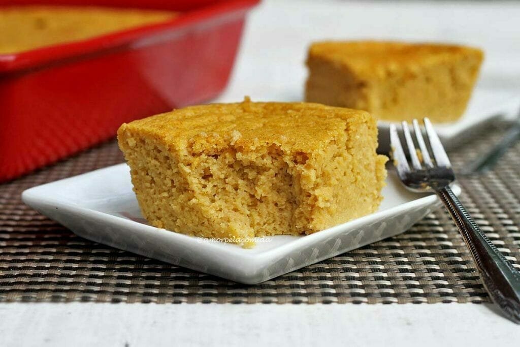 Duas fatias quadradas de bolo de fubá sobre pratos quadrados pequenos