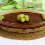Travessa oval de vidro com uma sobremesa em duas camadas, a camada de baixo é um creme branco com uvas verdes e por cima uma cobertura cremosa de chocolate
