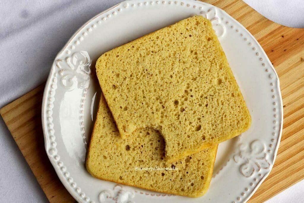 Duas fatias de pão quadrado sobre prato redondo, a fatia de cima está mordida