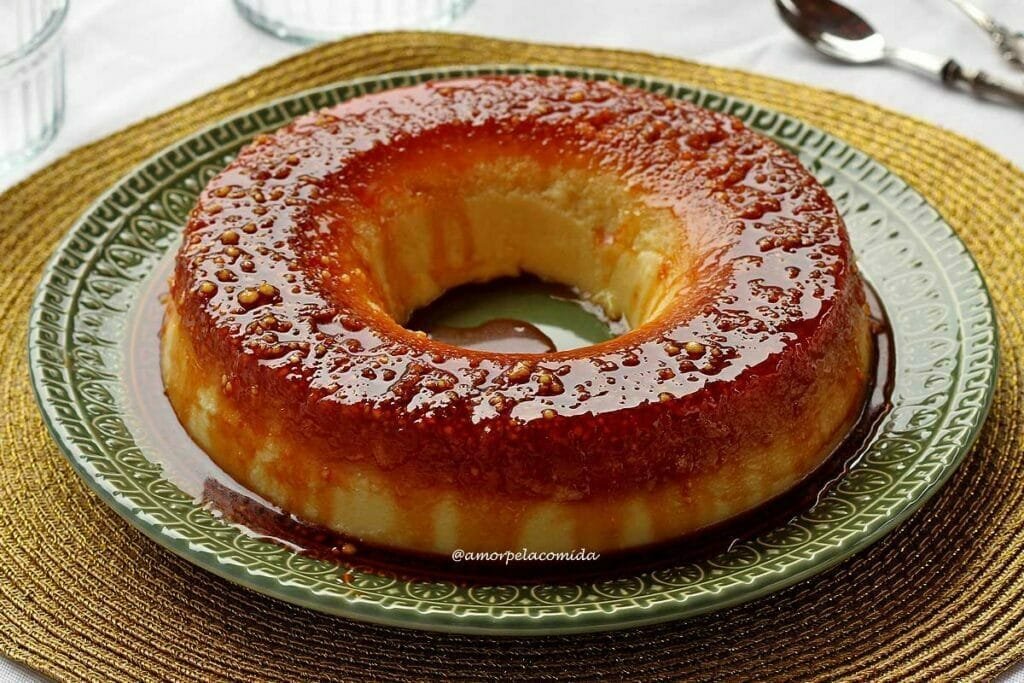 Pudim redondo com furo no meio, no topo tem uma calda de caramelo e bolinhas pequenas de tapioca granulada