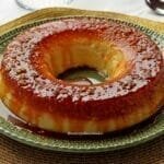 Pudim redondo com furo no meio, no topo tem uma calda de caramelo e bolinhas pequenas de tapioca granulada