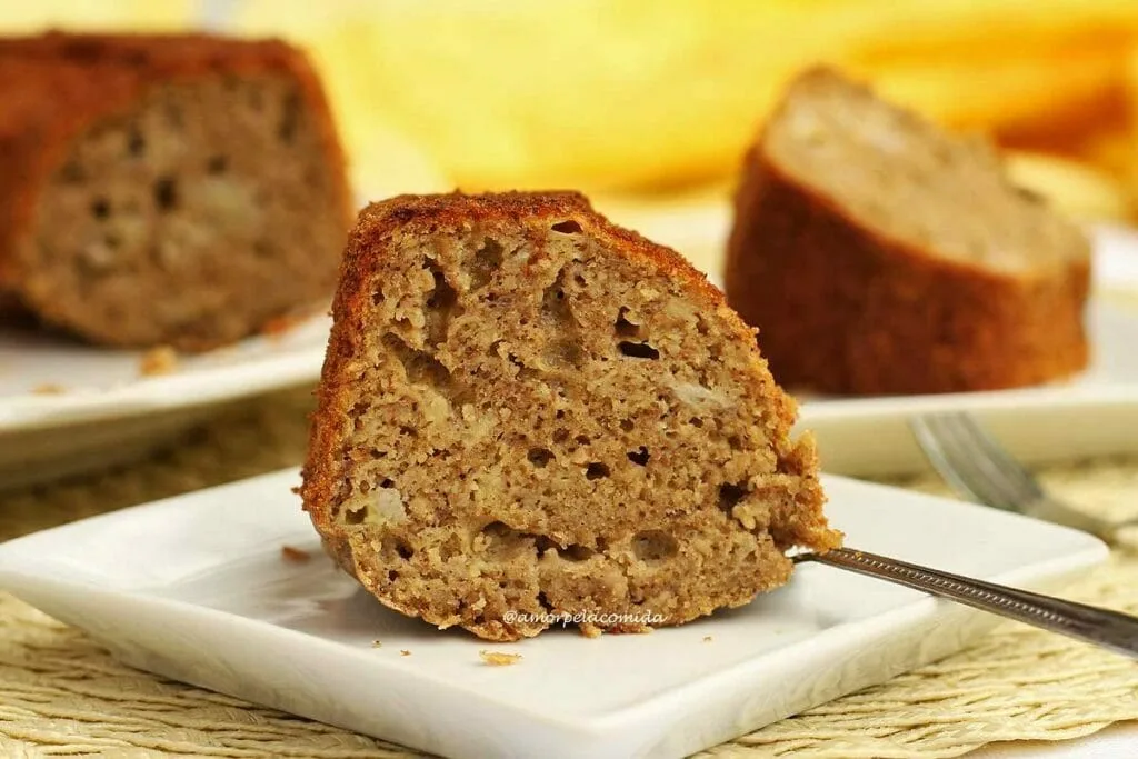Une tranche posée sur une petite assiette carrée, derrière une tranche posée sur une autre assiette et une partie du gâteau déjà cassé montrant