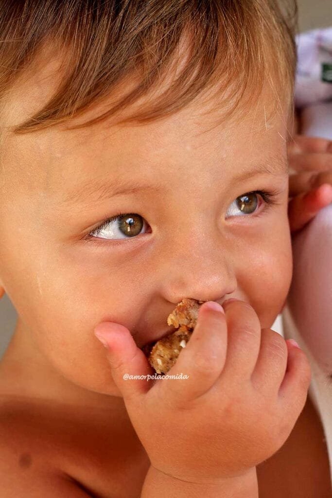 Menino de quase 2 anos, branco, loiro, comendo um pedaço de bolo