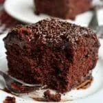 Fatia de bolo de chocolate com cobertura de chocolate que já foi comido alguns pedaços e o garfinho está ao lado da fatia