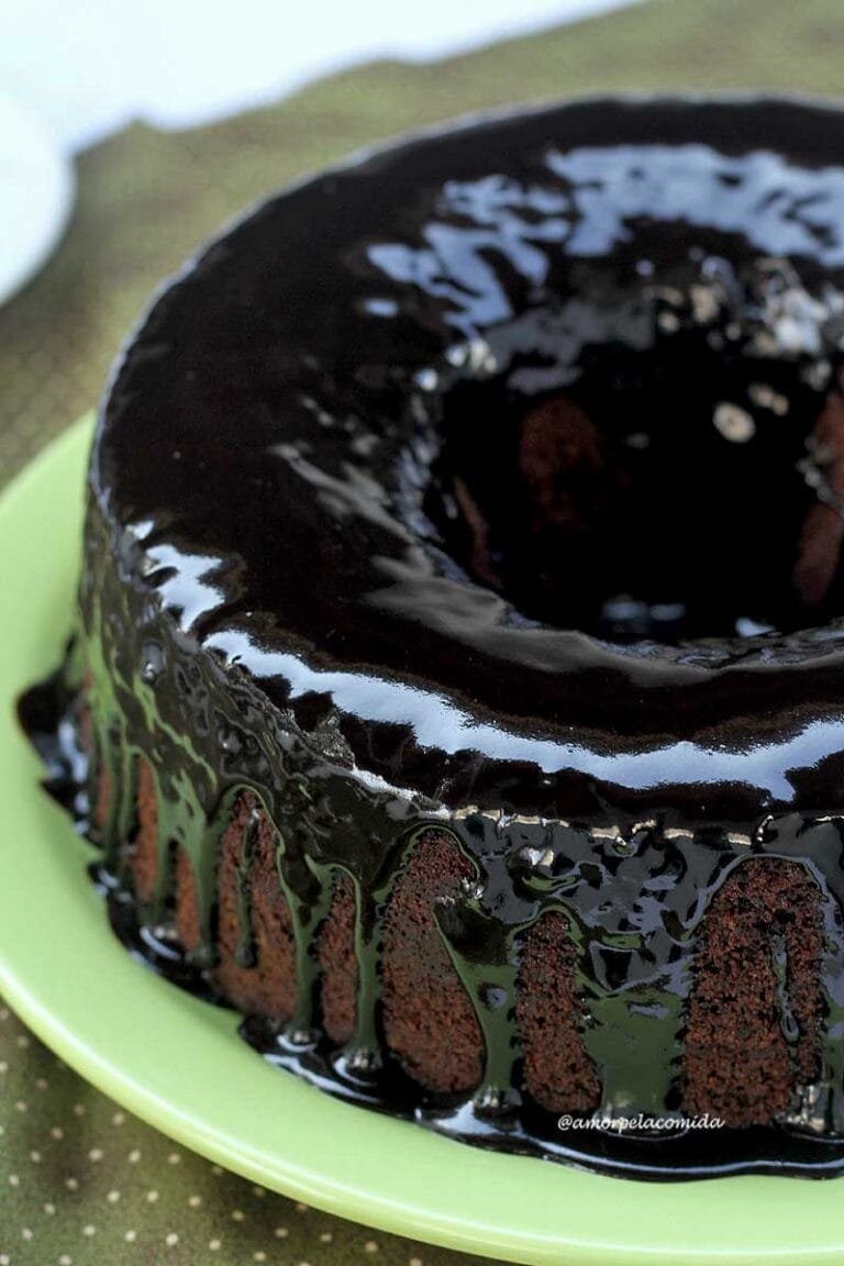 TARTA DE CHOCOLATE ESPONJA Y HÚMEDA SIN TRIGO SIN LACTOSA Pastel redondo con agujero en el medio hecho de chocolate con glaseado de chocolate en un plato verde claro