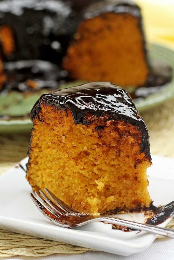 Fatia de bolo de cenoura que já foi comida uma parte utilizando um garfo, o garfo está ao lado do pedaço