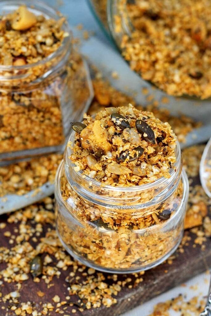 Vidrinhos de granola salgada com sementes sobre tábua de madeira