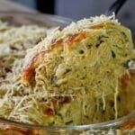 Colherada de frango desfiado cremoso com cobertura de queijo e batata palha sobre a travessa de fricassê