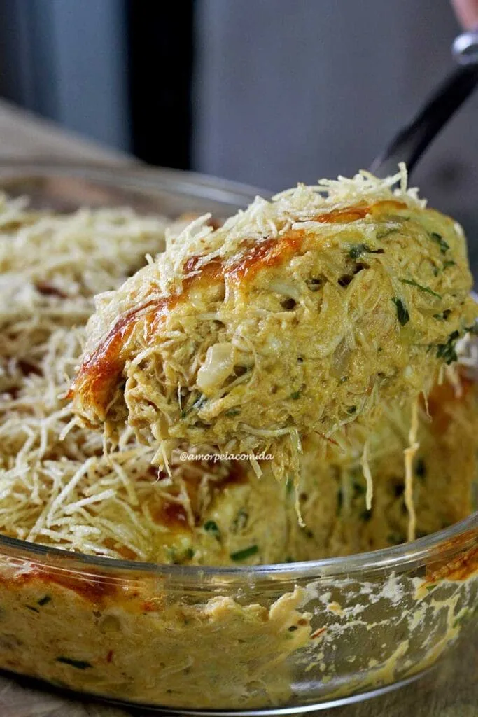 Spoonful of creamy shredded chicken topped with cheese and potato chips on a fricassee dish