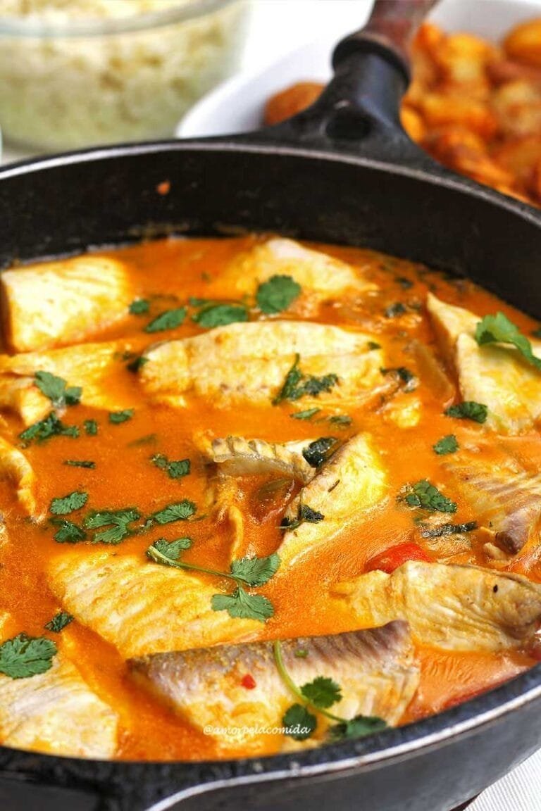 TILAPIA MOQUECA Grande padella nera con pesce in salsa cremosa a base di latte di cocco, olio di palma, pomodoro, cipolla e pepe