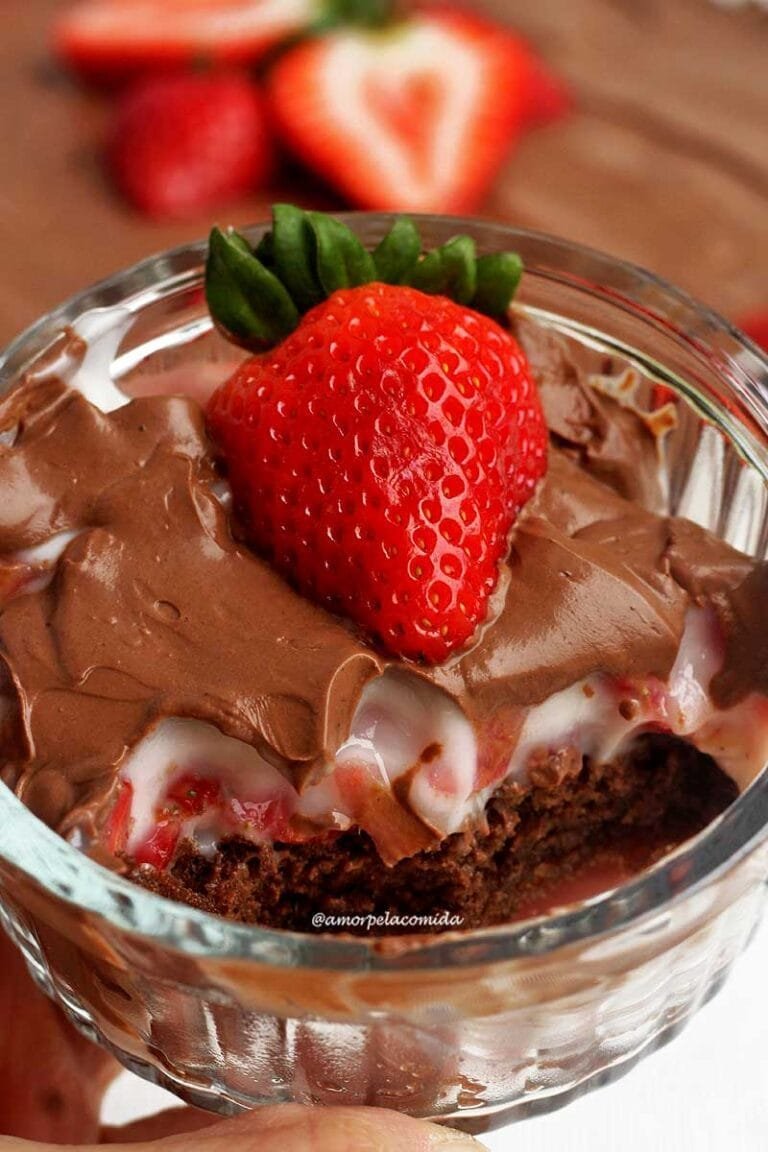 SOBREMESA DE MORANGO COM CHOCOLATE NA TRAVESSA Pote de vidro redondo, canelado com sobremesa de morango dentro, por baixo bolo de chocolate, no meio creme com morango e por cima chocolate e um morango decorando