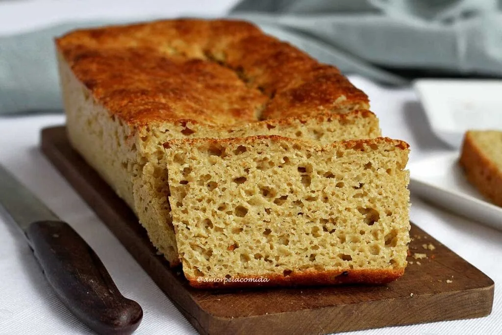 Sliced bread on a rectangular wooden board on a table with a cloth tablecloth