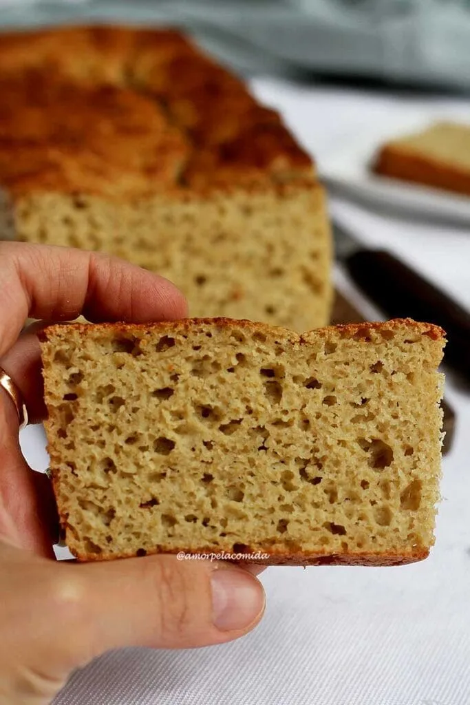 Hand holding slice of bread showing the airy texture of the dough