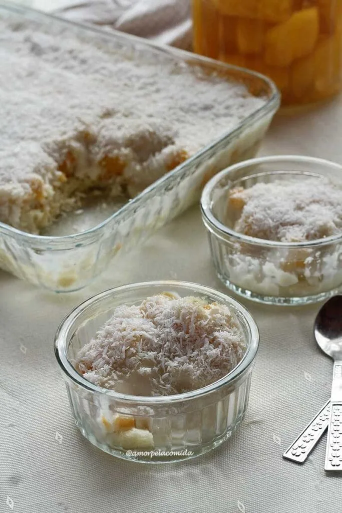 Two glass jars with peach dessert inside, in the background a dish with more dessert