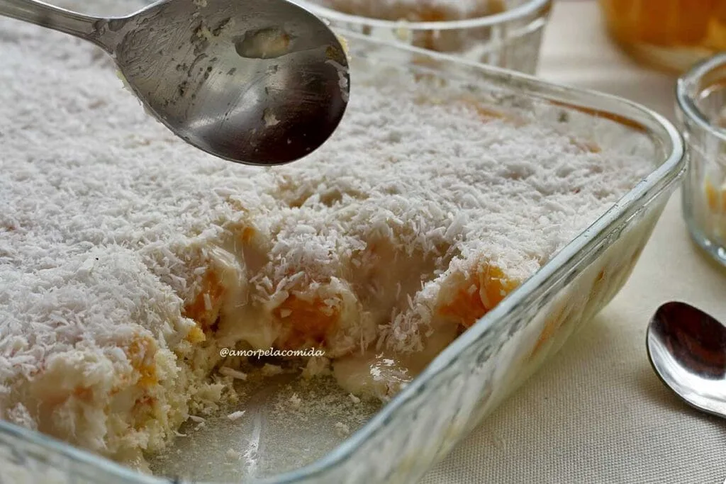 Metal spoon on glass serving dish with peach and cream dessert